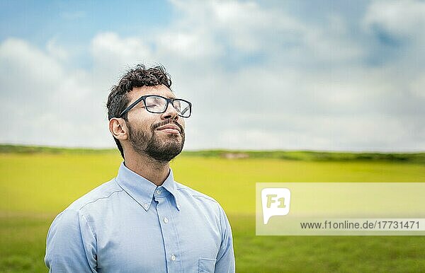 A young person breathing fresh air in the field  Man breathing fresh air in the field  Happy guy breathing fresh air in the grass