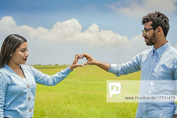 Glückliches Paar  das mit seinen Händen eine Herzform bildet  verliebtes Paar auf dem Feld  schönes Paar auf dem Feld