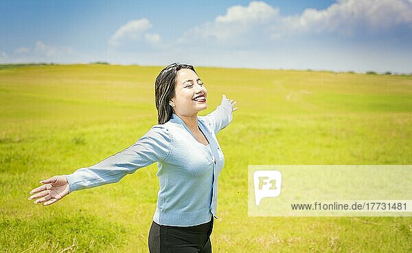 Junge Frau lächelt und breitet ihre Hände im grünen Feld  Konzept der Frau atmet frische Luft im Feld  Glückliche Frau atmet frische Luft im Feld und breitet die Arme aus