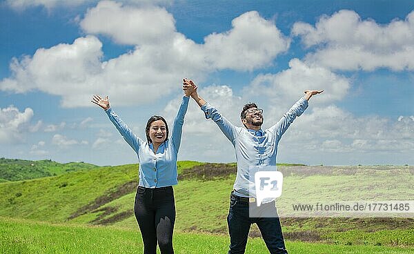 Concept of a happy and free couple in the field  Couple on the hill with hands raised to the sky  Happy couple in the field raising hands to the sky