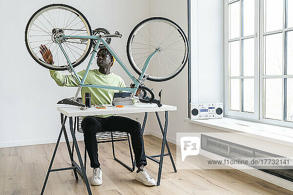 Young man repairing bicycle on table at home