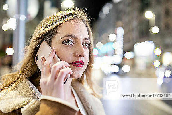 Young woman talking on smart phone in city