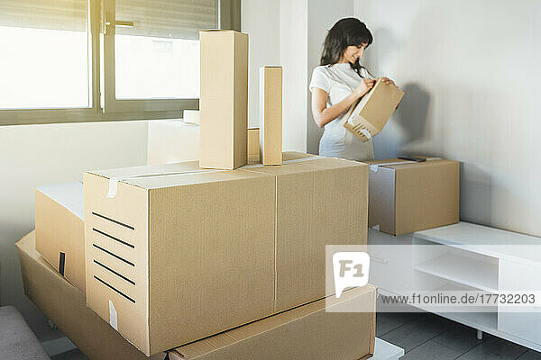 Woman unpacking cardboard boxes at new home