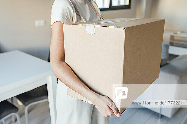 Woman with cardboard box standing at new home
