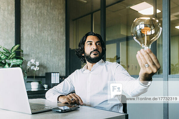 Businessman analyzing light bulb at office