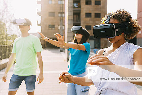 Multiracial friends wearing virtual reality simulator on sunny day