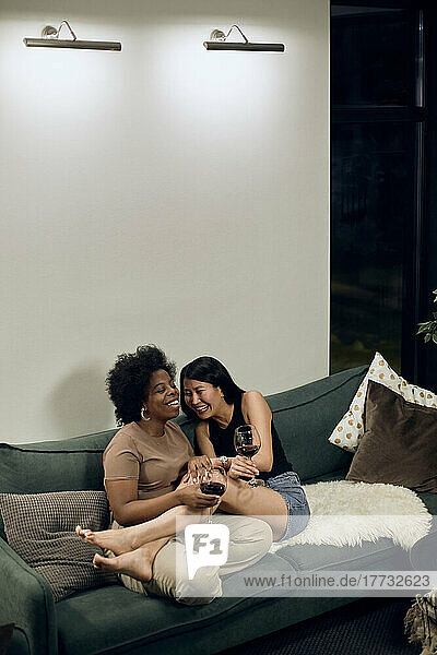 Lesbian couple laughing together on sofa at home