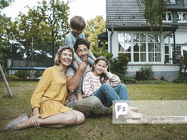 Happy family sitting on grass in back yard