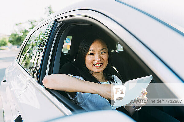Lächelnde Geschäftsfrau mit Tablet-Computer im Auto