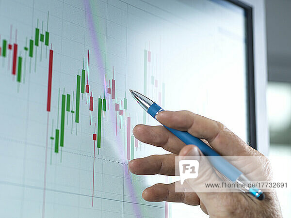 Mature trader analyzing share price on computer at office