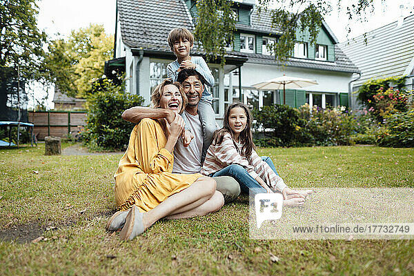 Happy family sitting in front of house at back yard