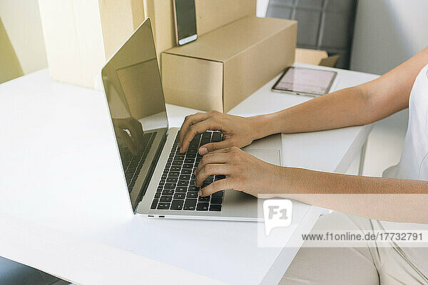 Hands of woman using laptop at table