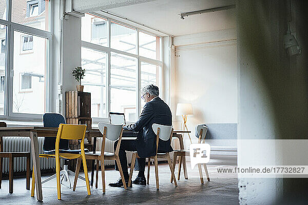 Senior businessman using laptop at desk in office