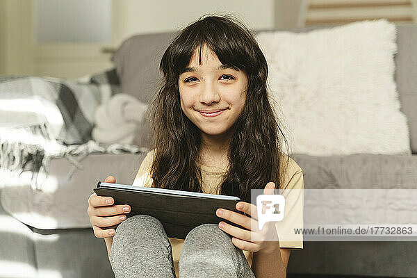 Lächelndes Mädchen mit Tablet-PC im Wohnzimmer
