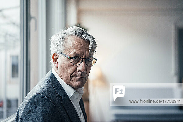 Senior businessman wearing eyeglasses in front of window at office