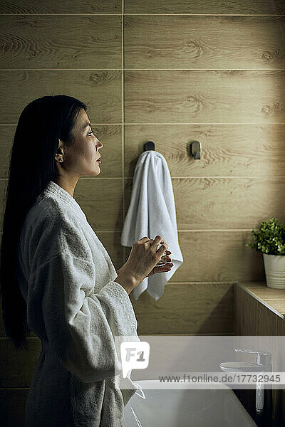 Woman wearing bathrobe doing skincare routine
