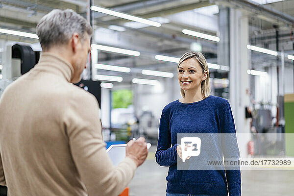 Businesswoman smiling at colleague in factory