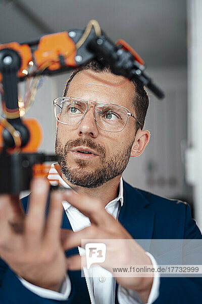 Geschäftsmann mit Brille untersucht Robotermodell