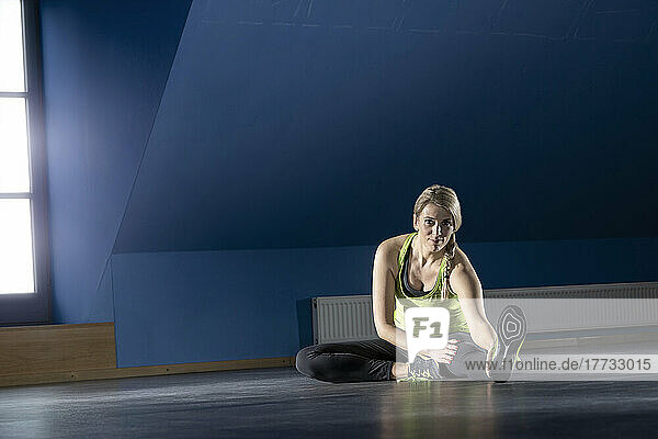 Woman doing stretching exercise sitting on floor at fitness room