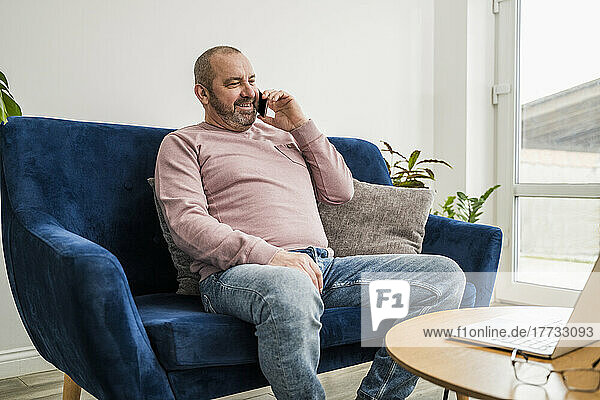 Smiling businessman talking on mobile phone in living room