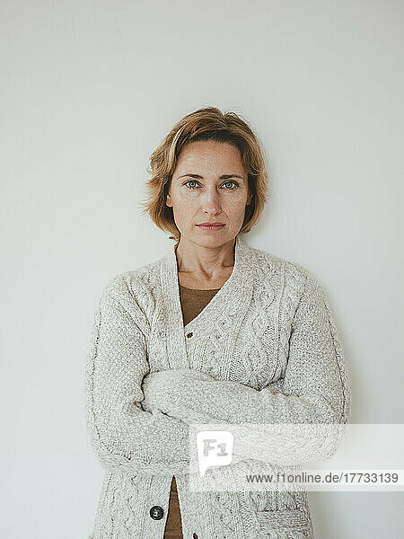 Mature woman wearing sweater standing in front of wall
