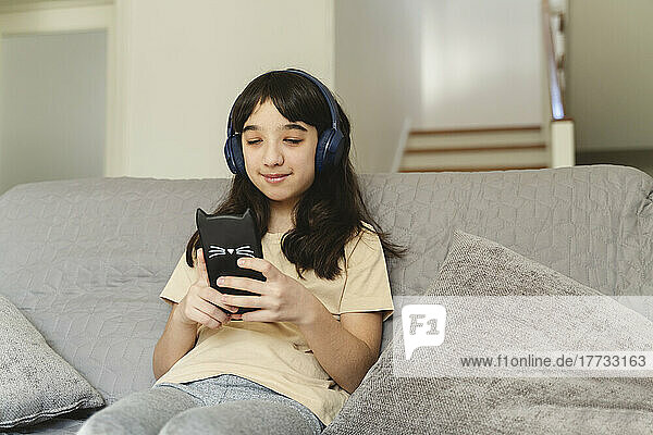 Girl listening music and using smart phone in living room