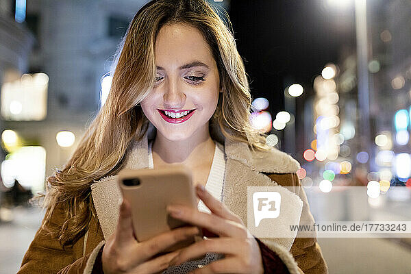 Lächelnde Frau  die Textnachrichten auf dem Smartphone sendet