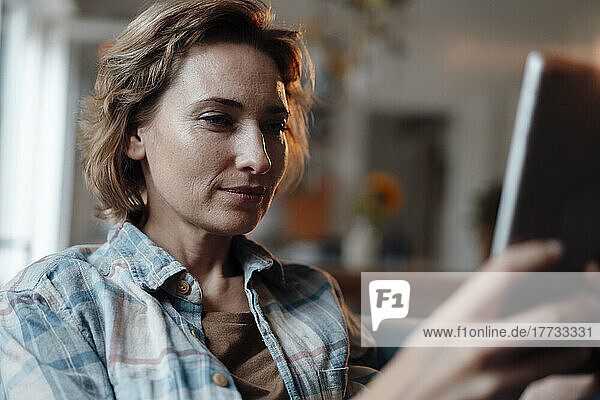 Mature woman using tablet PC at home