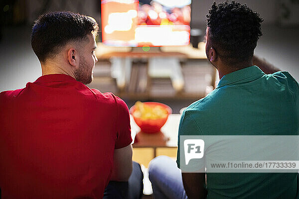 Männer reden miteinander und schauen sich zu Hause ein Fußballspiel an