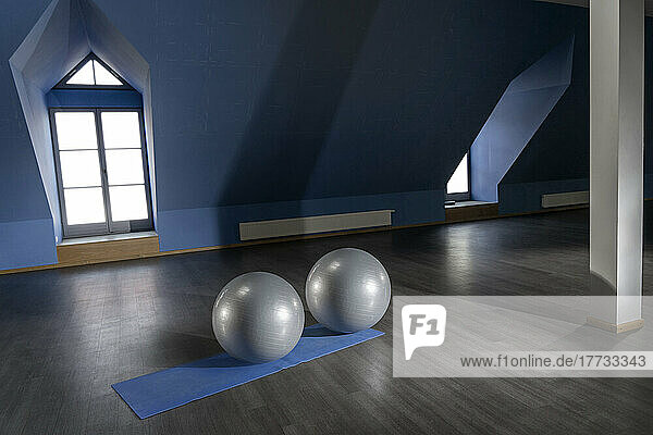 Gray color exercise balls on mat in empty fitness room