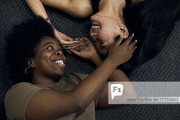 Cheerful lesbians lying on floor at home
