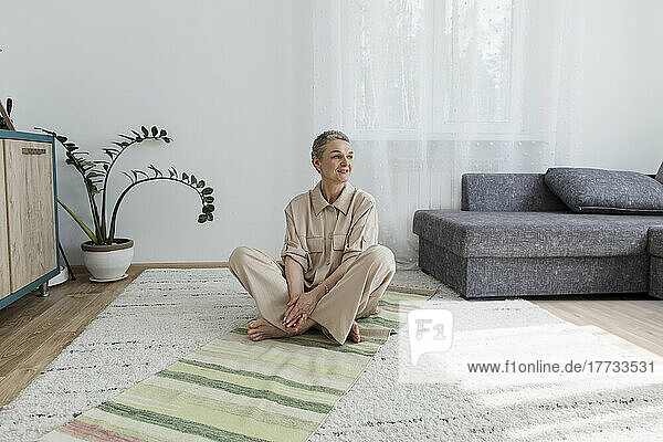 Mature woman with sitting on rug at home
