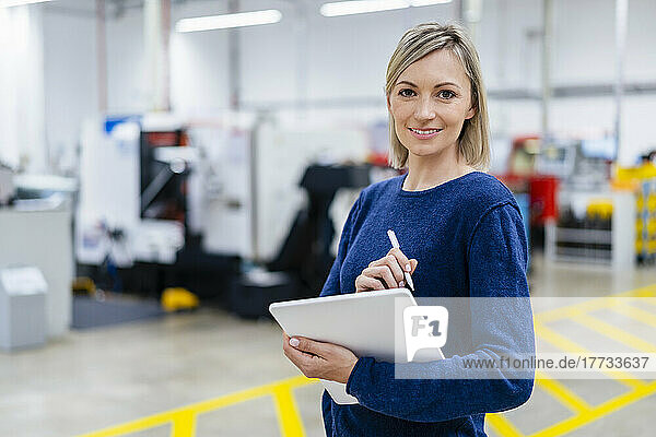 Porträt einer lächelnden Geschäftsfrau mit digitalem Tablet in der Fabrik