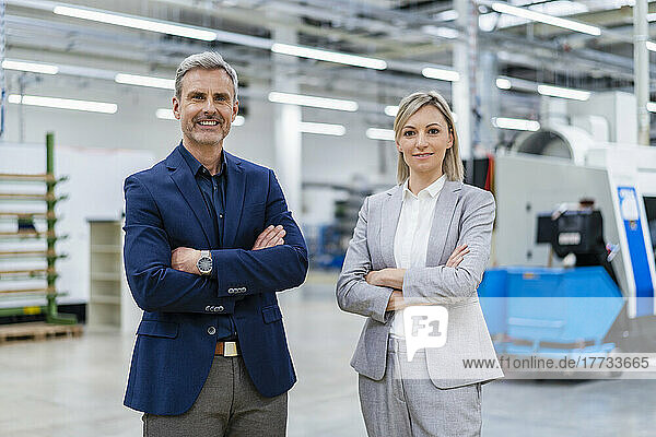 Portrait of confident businessman and businesswoman in factory