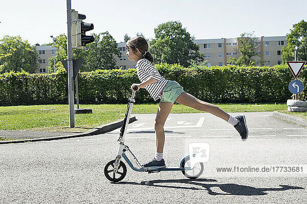 Girl riding push scooter on traffic course