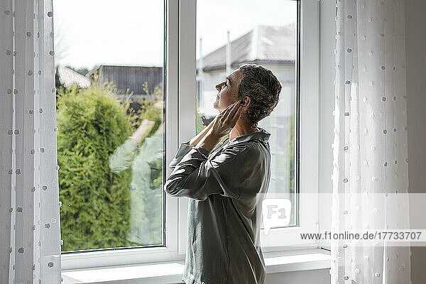 Mature woman standing at the window at home
