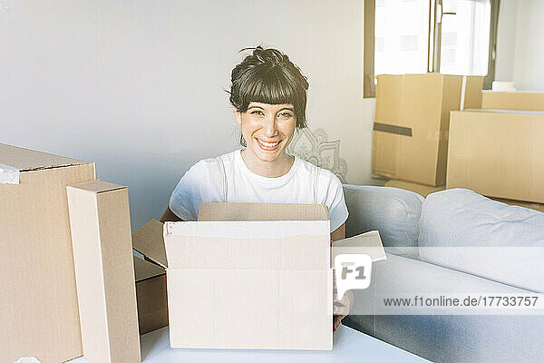 Happy woman with cardboard boxes sitting in living room at home