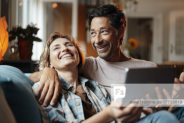 Happy man and woman with tablet PC sitting at home