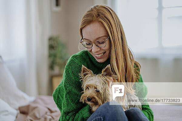 Happy woman sitting with Yorkshire Terrier at home