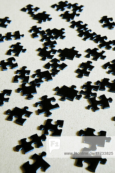 Studio shot of black jigsaw pieces flat laid against white background