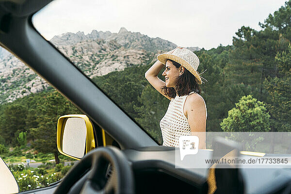 Woman wearing hat seen from van windshield