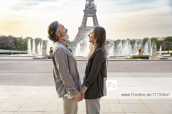 Happy mature couple holding hands standing in front of Eiffel Tower  Paris  France
