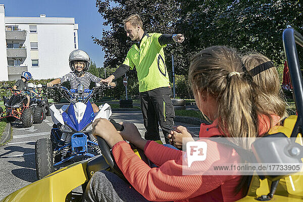 Young instructor assisting boy driving quadbike at traffic education training