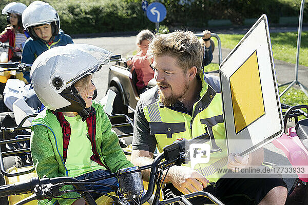 Trainer ecplaining traffic sign to boy sitting in quadbike