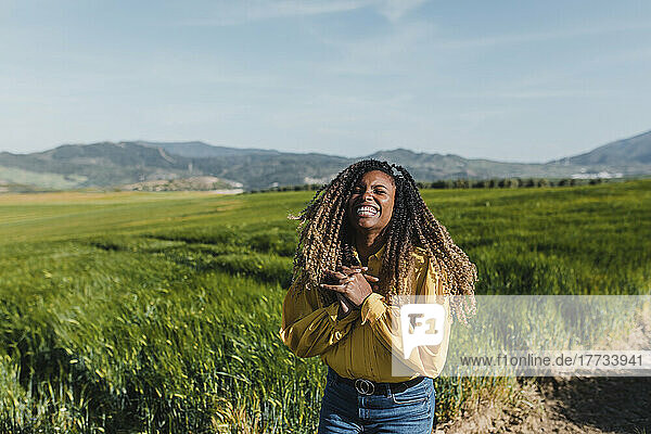 Cheerful woman with eyes closed standing in meadow