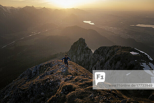 Wanderer steigt bei Sonnenuntergang auf den Berggipfel
