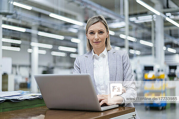 Portrait of businesswoman with laptop in factory
