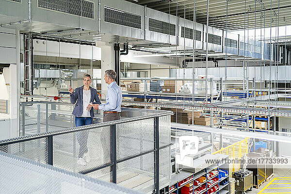 Businessman and businesswoman talking in factory
