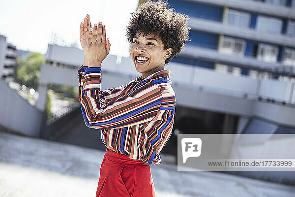Happy woman with Afro hairstyle clapping hands at parking deck