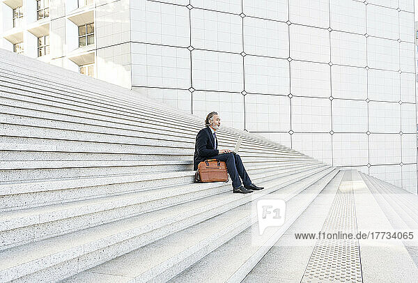 Businessman with laptop sitting on steps